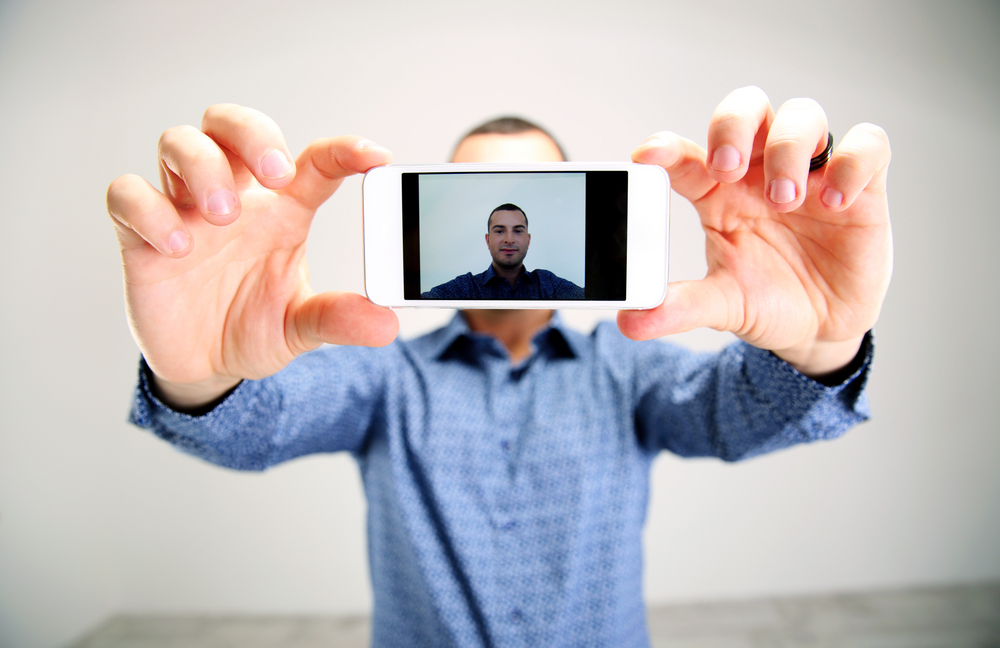 Portrait of a man taking selfie. Focus on smartphone